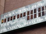 После того, как сумма долга преодолела планку 10 трлн долл, так называемые "Часы национального долга" зашкалили и то что раньше было знаком доллара поменялось на цифру 1, а доллар приклеили рядом