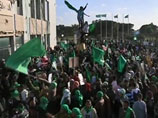 Cотни сторонников режима, собравшиеся в эти часы на площади возле укрепленного комплекса Баб аль-Азизия на окраине Триполи, скандируют лозунги в его поддержку