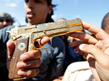 Аш-Шайбани держит в руках золотой 9-миллиметровый пистолет, который он якобы забрал у свергнутого ливийского лидера перед тем, как убить его