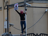 Активистка Татьяна Романова в лиловой балаклаве на голове вначале залезла на фонарный столб у турецкой дипмиссии, расположенной напротив здания суда и скандировала лозунги в поддержку приговоренных девушек