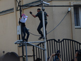 Полицейские стали уговаривать ее слезть, но девушка перебралась на забор посольства Турции, а затем перелезла на другую сторону сетки поверх ограды, оказавшись на территории иностранного государства