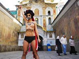 У "секстремистки", как называет своих активисток Femen, был разрисован не только бюст, но и лицо. Девушка символизировала собой "ангела смерти" с серпом в руке и мрачным венком. На теле у нее была надпись "Диктатура должна умереть"