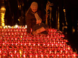 Девушка зажигает лампаду во время проведения траурных мероприятий в День памяти жертв Голодомора на площади перед памятником Тарасу Шевченко во Львове