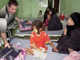 Член американской гуманитарной организации раздает игрушки и одежду больным иракским детям