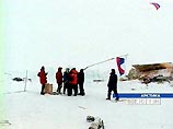 Полярники на льдине снимают флаг российской экспедиции и готовятся к посадке на вертолет Полярники на льдине снимают флаг российской экспедиции и готовятся к посадке на вертолет
