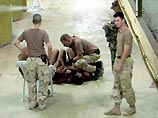 На другой фотографии изображен американский солдат, который давит коленом на шею одному из троих заключенных, лежащих на полу