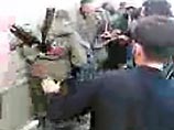 Одного федерала, который еще на ногах, люди в кадыровских формах подгоняют тычками туда же, где лежат остальные. Толпа напирает, размахивает ногами, кулаками, прикладами Одного федерала, который еще на ногах, люди в кадыровских формах подгоняют тычками туда же, где лежат остальные. Толпа напирает, размахивает ногами, кулаками, прикладами