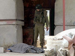 На фото израильский солдат смотрит на тело сотрудника службы безопасности, убитого вблизи населенного пункта Туль-Карема