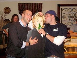 На скандальной фотографии, попавшей в социальную сеть Facebook, Джон Фавро обнимает картонную Клинтон и держит ее за грудь