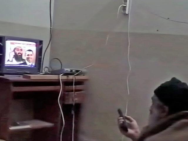 Держа в руках пульт дистанционного управления, Усама, по-видимому, пересматривает сообщения международных телеканалов о своих выступлениях в бытность главарем террористов