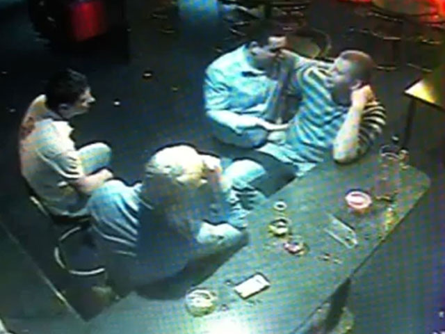 На записи видно, как четверо молодых мужчин сидят за столиком в баре и о чем-то оживленно беседуют