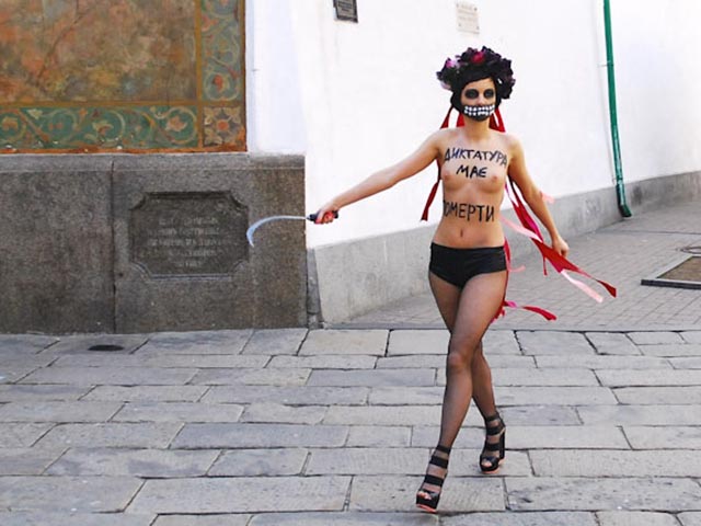 Полуобнаженная активистка движения Femen с серпом в руке демонстрировала возле Киево-Печерской лавры неотвратимость наказания за жестокий разгон Евромайдана в Киеве 30 ноября