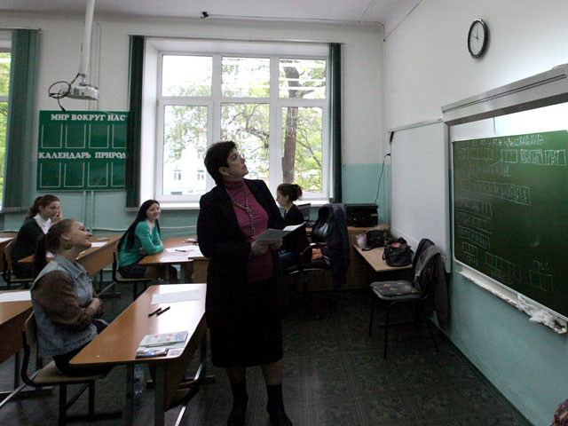 Преподаватель смотрит на часы перед началом сдачи единого государственного экзамена по русскому языку в средней образовательной школе города Владивостока