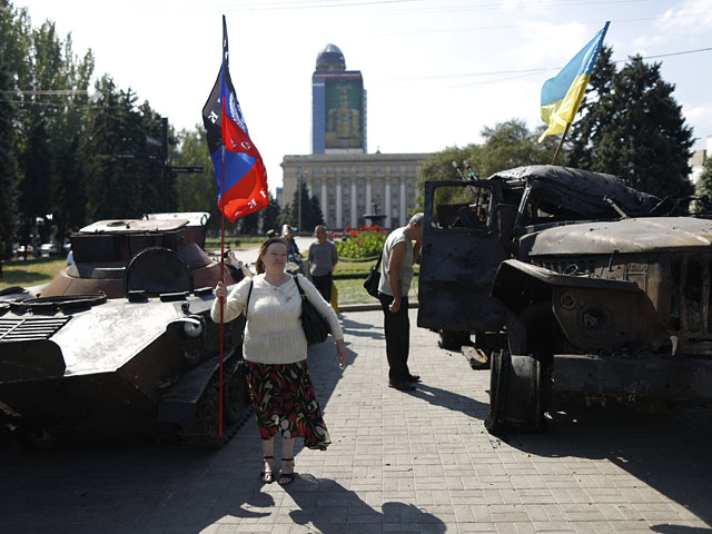 Женщина с флагом Донецкой народной республики у подбитой украинской военной техники на площади Ленина в Донецке