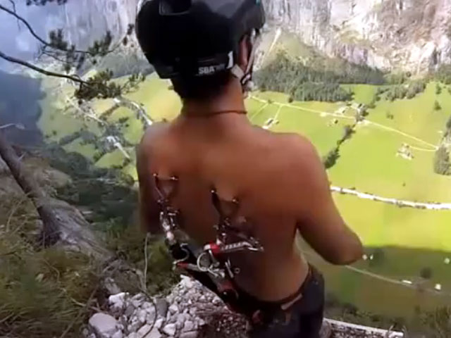 Российский бейсджампер Станислав Аксенов поразил коллег смелым трюком, исполнив прыжок со скалы с парашютом, прикрепленным только к пирсингу на своей спине
