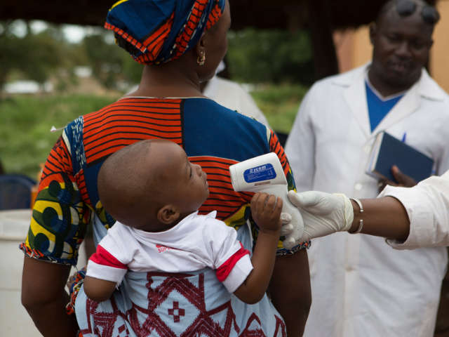 Медработник проверяет температуру ребенка, пересекающего границу Мали и Гвинеи 2 октября 2014 года.