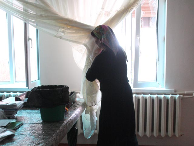 Женщина убирает выбитые взрывом стекла в доме, рядом с районным отделением внутренних дел в селении Серноводск. Взрыв произошел в сентябре 2013 года