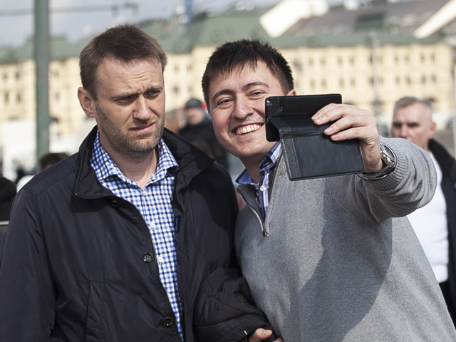 Кремль, "обеспокоенный популярностью" оппозиционера Алексея Навального (слева), негласно запретил чиновникам и главам государственных компаний упоминать в публичных выступлениях его имя, рассказали Bloomberg сразу три источника, знакомых с ситуацией