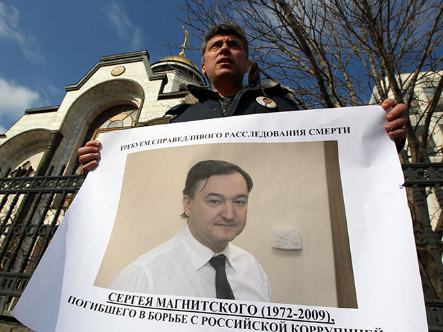Борис Немцов держит в руках плакат с изображением Сергея Магнитского во время одиночного пикета против "полицейского произвола" у здания МВД РФ в Москве в 2012 году