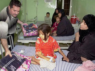 Член американской гуманитарной организации раздает игрушки и одежду больным иракским детям