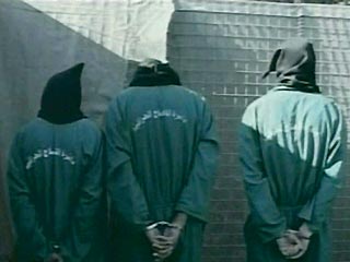 На этой видеозаписи заключенные в капюшонах и зеленых костюмах со связанными руками за спиной стоят у стены в ожидании казни