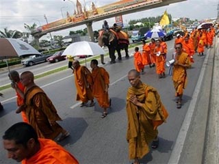 Пестрая толпа монахов в ярко-оранжевых робах и верующих в белых одеждах прошла под желтыми флагами и плакатами в сопровождении девяти слонов около 30 километров из западных пригородов Бангкока к зданию парламента