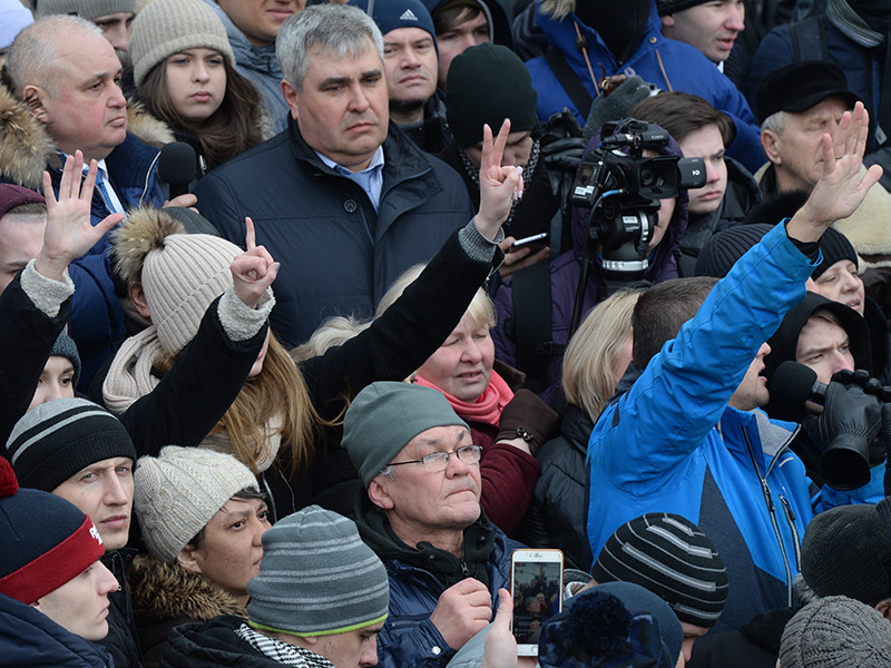 Люди показывают на пальцах сколько родственников у них погибло при пожаре в торгово-развлекательном центре «Зимняя вишня» во время митинга на площади Советов у здания администрации в Кемерово