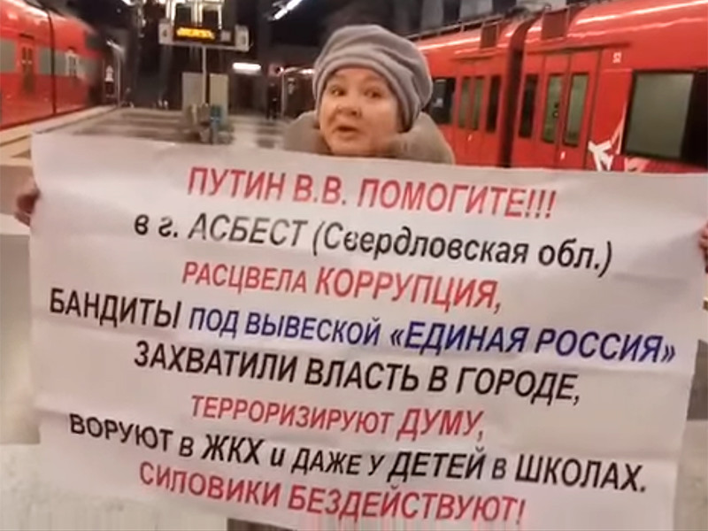 На видео женщина держит плакат с другой надписью: призывом к Путину остановить коррупцию в Асбесте