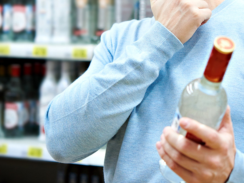 Фото: мужчина выбирает водку в супермаркете