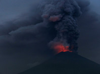 Над вершиной вулкана поднимаются темный дым и пепел на высоту 3400 м, а из кратера вырывается пламя