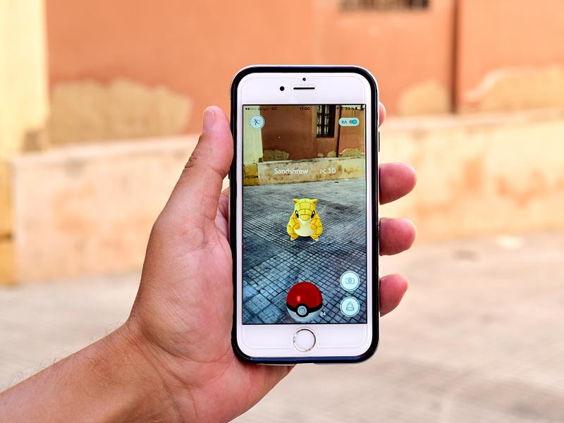 Фото: человек играет в Pokemon Go на улице города