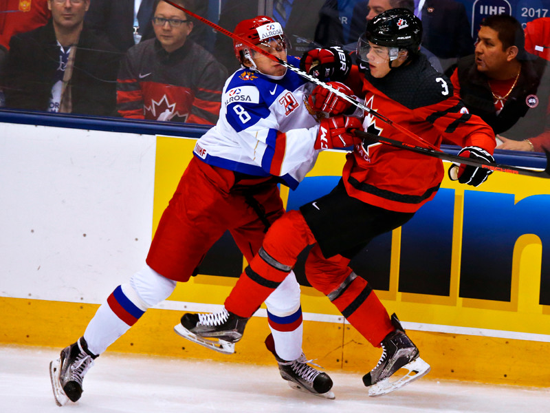 Игрок сборной России Кирилл Ураков и игрок сборной Канады Ноа Юулсен (справа) в матче молодёжного чемпионата мира по хоккею